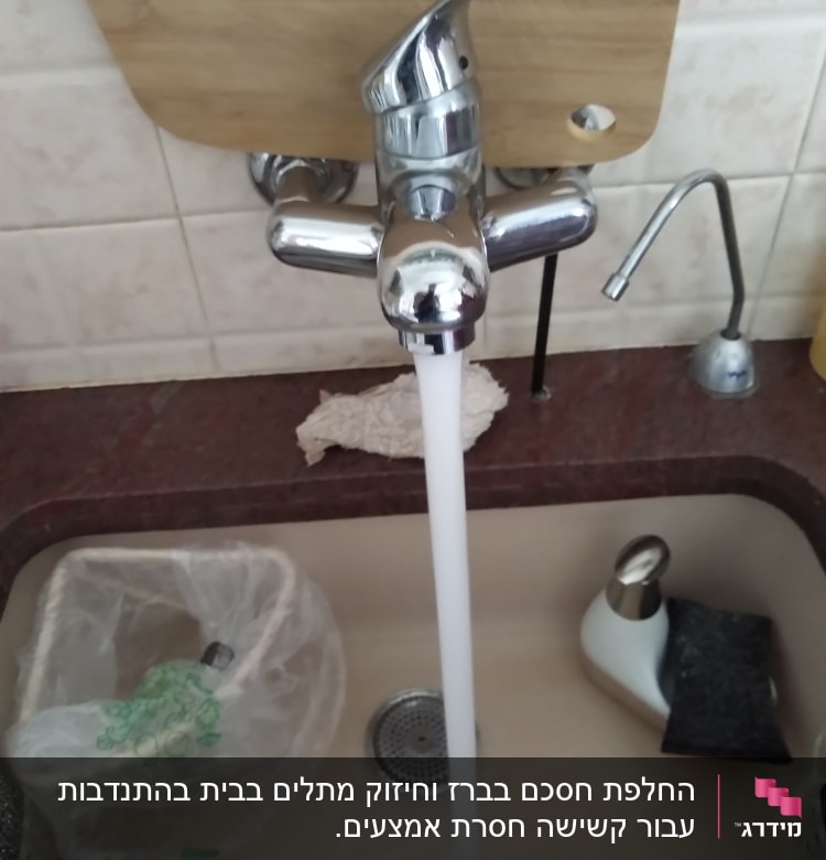 ברז מים זורם בכיור מטבח עם קרש חיתוך